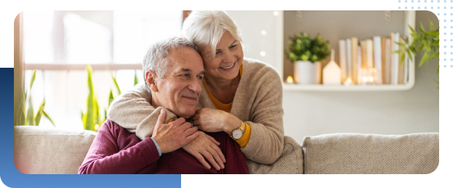 elderly couple sitting on the couch hugging each other